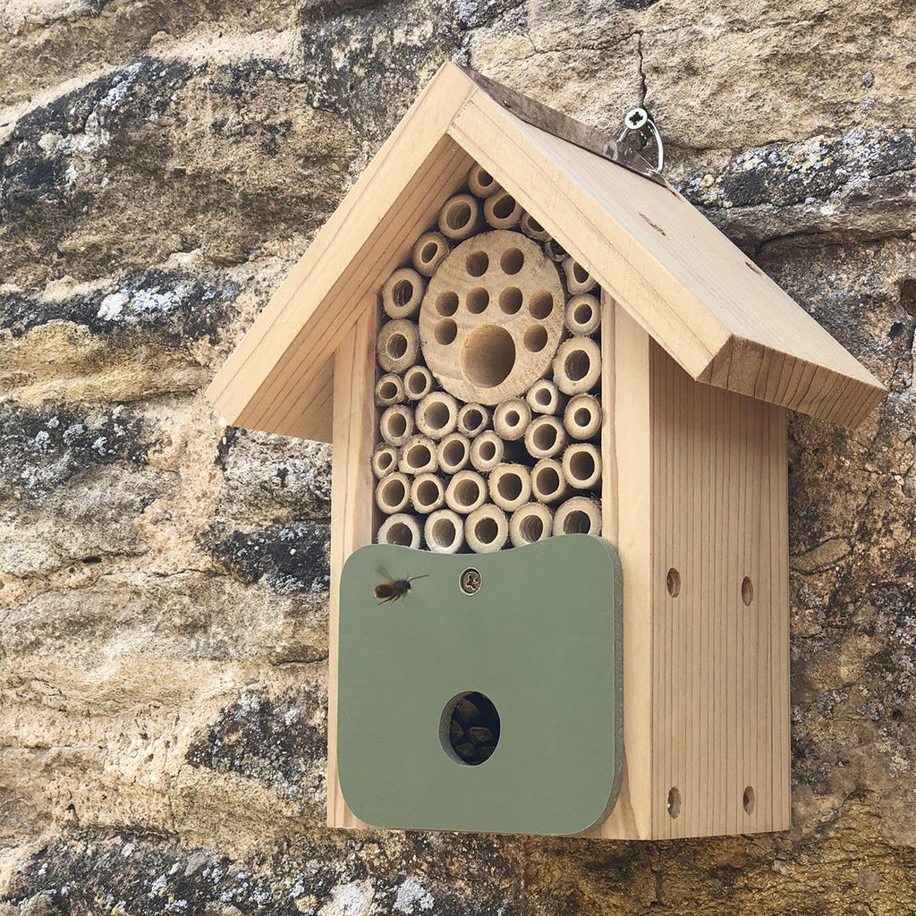 A bee hive mounted on a wall with lots of wooden tubes.