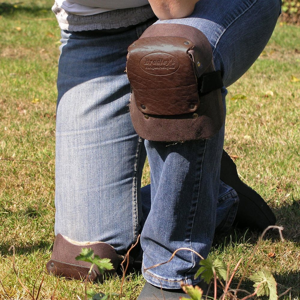 A man kneels with a leather knee pad on