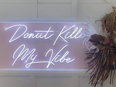 Custom LED neon sign reading 'Donut Kill My Vibe' in white, perfect for cafes, bars, and restaurants. This personalized LED light has low power consumption, is eco-friendly, and adds a fun, vibrant touch to any event or display.