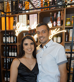 Laura S's testimonial image featuring Laura and her partner in front of a custom wedding LED neon sign that reads 'You & Me Always,' celebrating their engagement party.