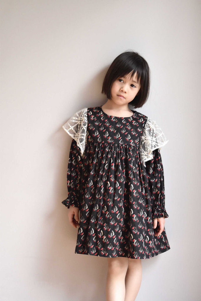 lulaland Fall No.15 Mirage collection. Girl wearing a black ruffled dress with leafy print and lace ruffles. Organic girl's clothes
