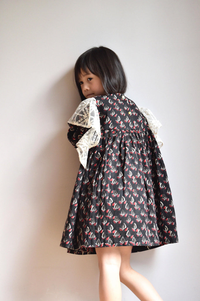 lulaland Fall No.15 Mirage collection. Girl wearing a black ruffled dress with leafy print and lace ruffles. Organic girl's clothes