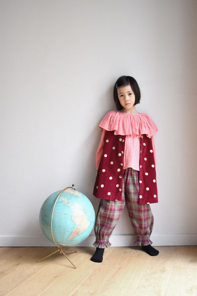 lulaland Fall No.15 Mirage collection. Girl wearing a pink blouse with collar, plaid pants and a red vest with polka dots. Organic girl's clothes