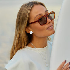 Close-up of woman with sunglasses, white clothes, and silver jewelry