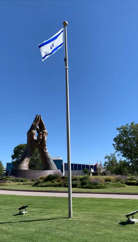 Statue with praying hands and the flag of Israel