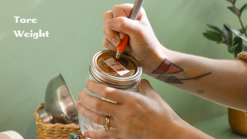 hands holding jar and sharpie, writing weight of jar on top