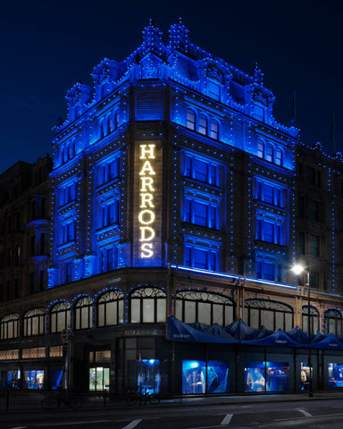 The Harrods storefront lit with Burberry Knight Blue lighting at night.