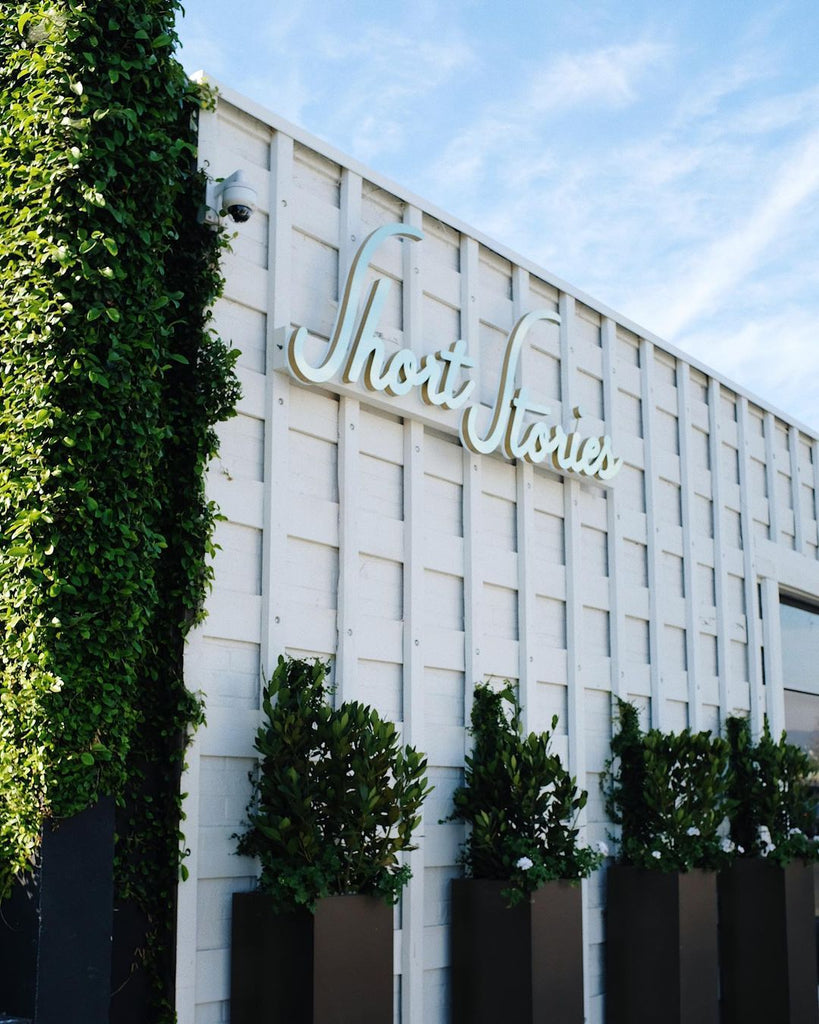 Photo of the exterior of the hotel with a sign that says, "Short Stories" with planters outside.