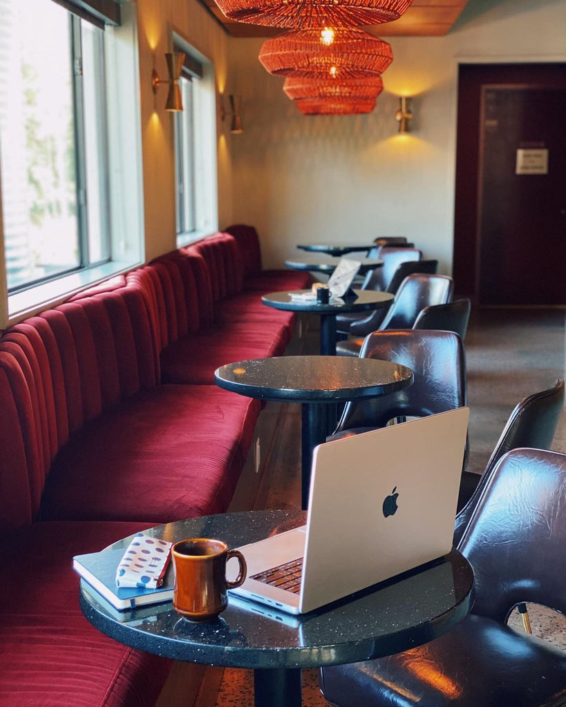 Photo at the Longleaf Lounge with bench seating and tables with coffee and a computer.