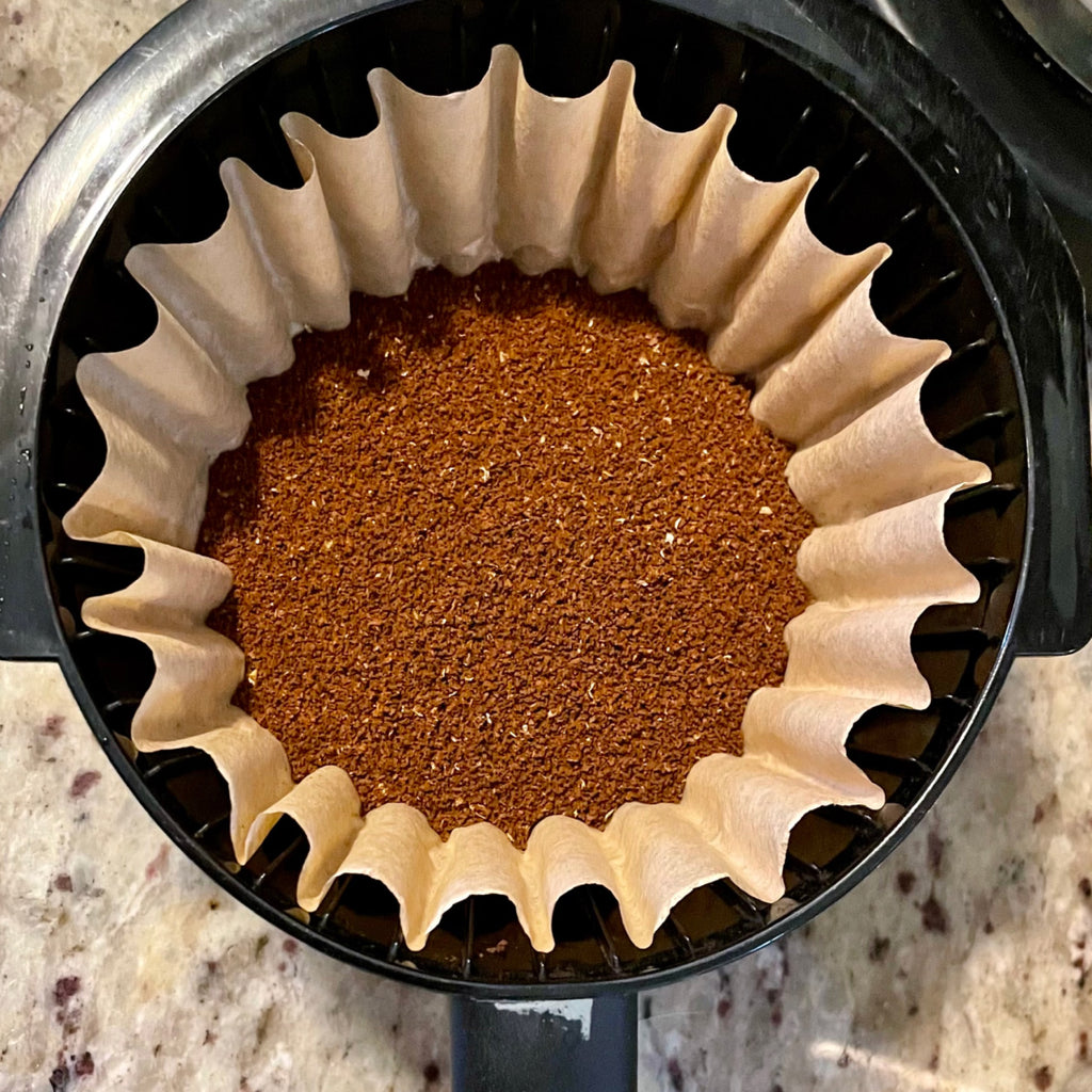 Top-down photo of coffee grounds in a filter in a coffee maker.