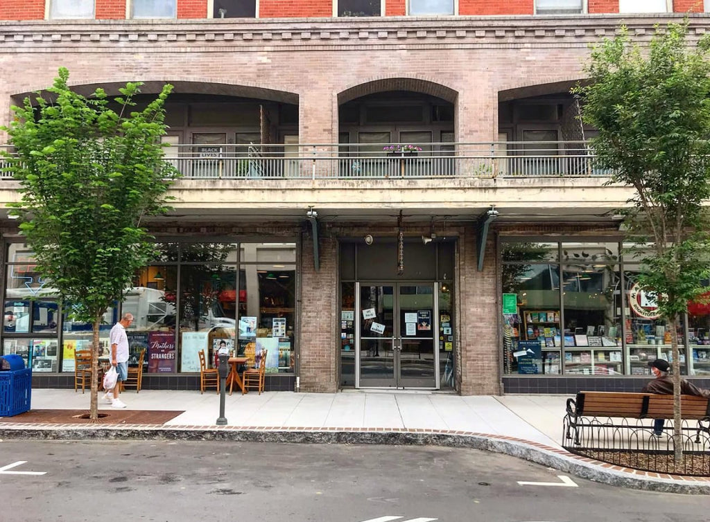 Exterior of Malaprop's Bookstore. There is a balcony on the second story and leafy trees out front.