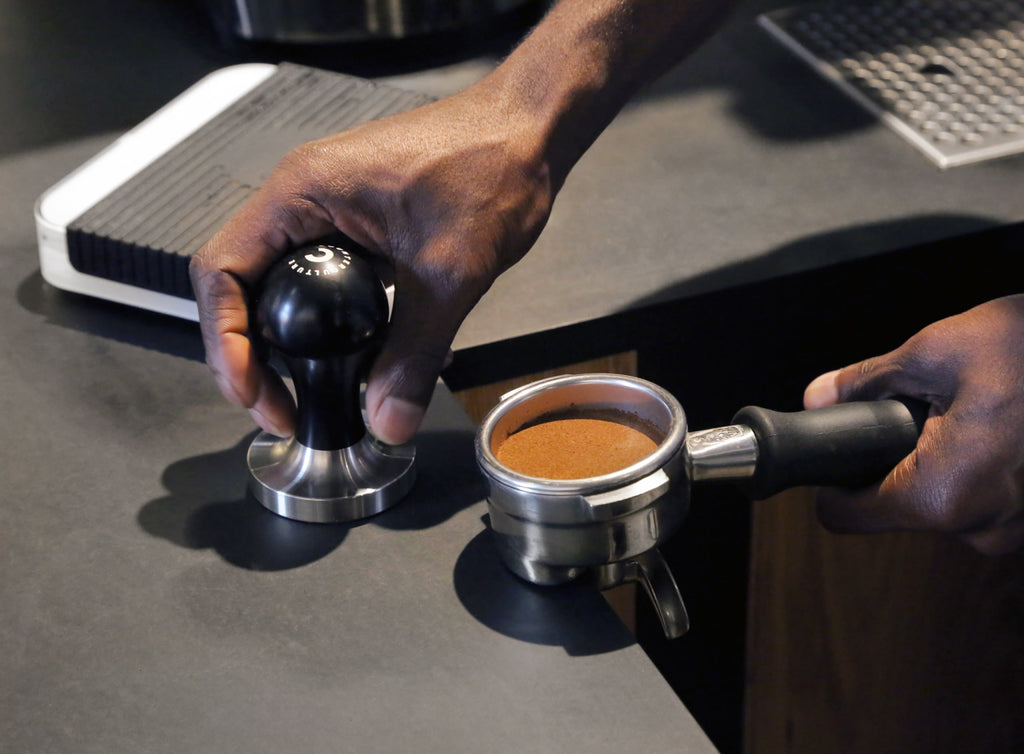 Photo of a person tamping espresso.