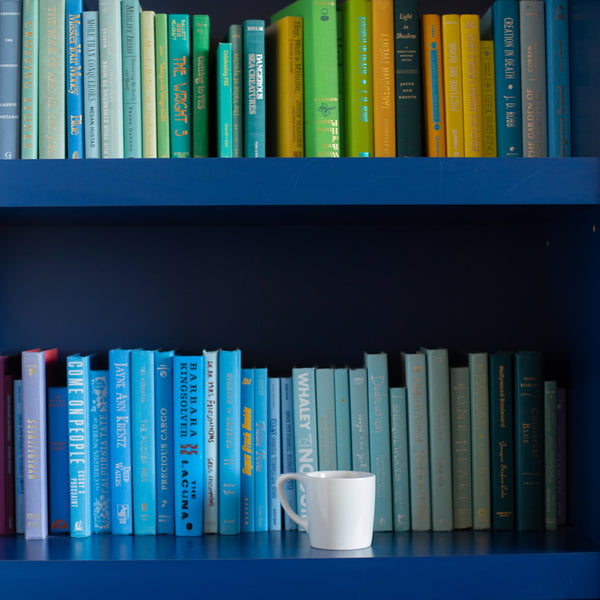 Photo of a bookshelf full of books with a mug of coffee.