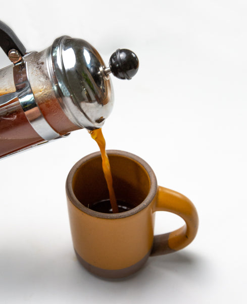 Image of coffee being poured into a mug from a French press.