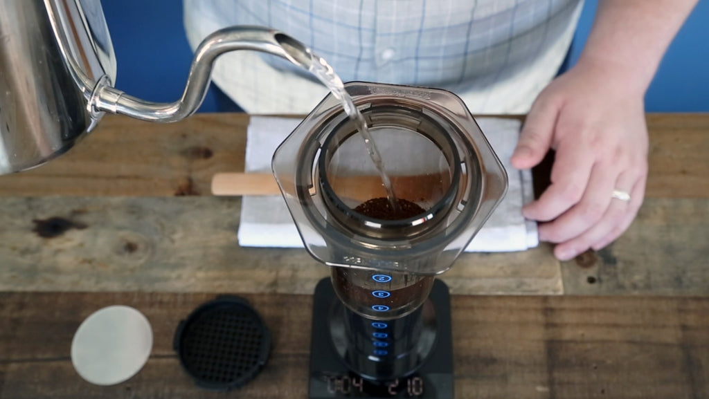 Top-down photo of a person pouring water into an AeroPress
