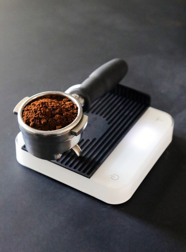 Photo of a portafilter filled with ground coffee.