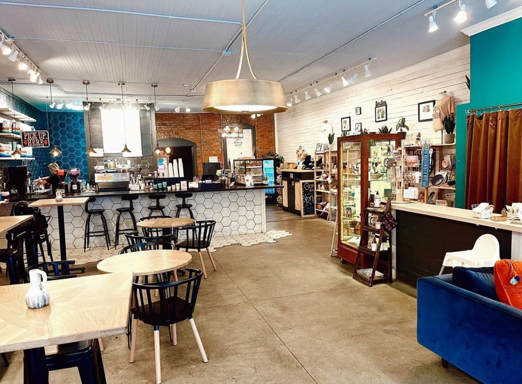 Photo of the interior of Mission Market. On the left there is a bar with high stools, and on the right along a wall there are shelves with products.