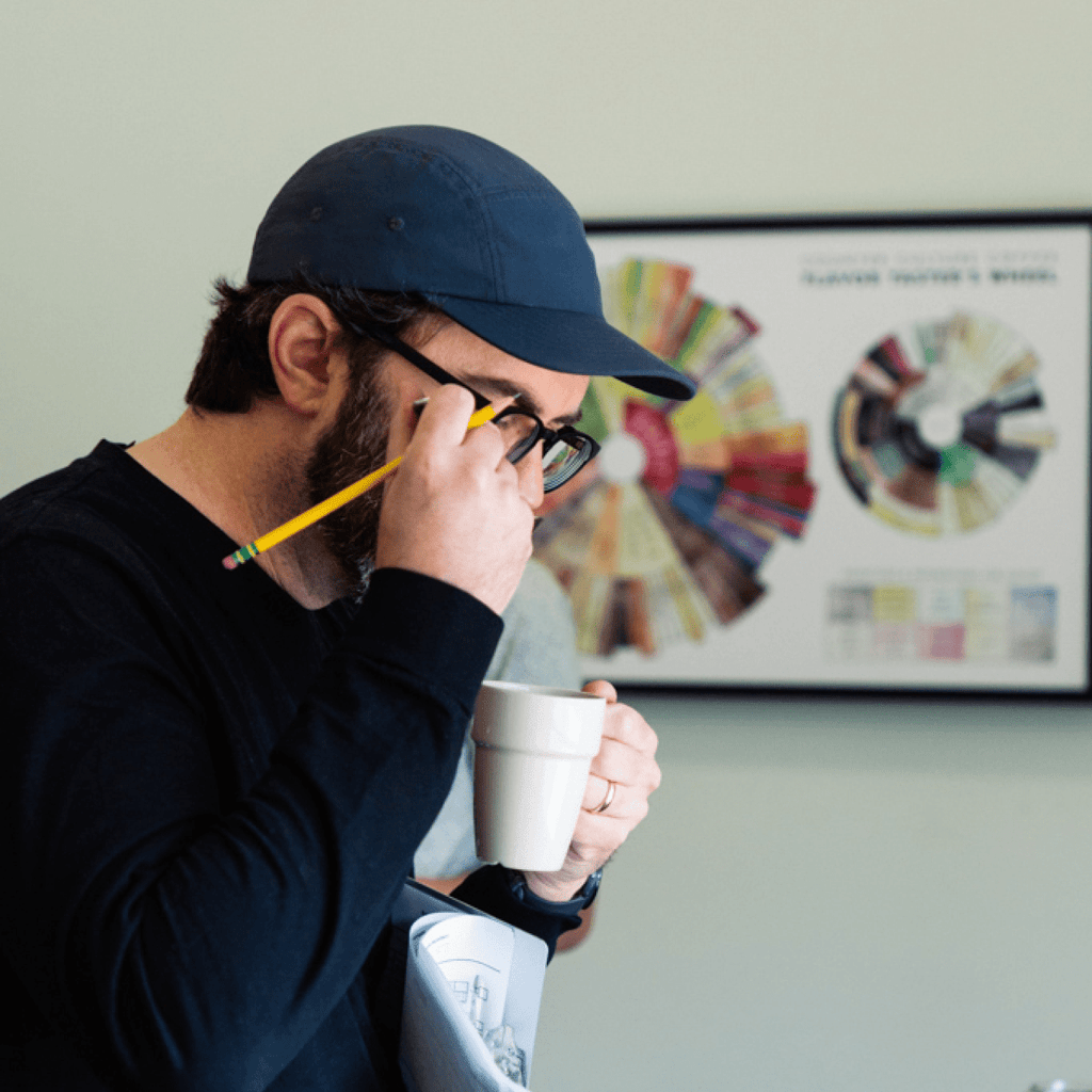 Photo of a person cupping coffee with a poster of the Counter Culture Coffee Taster's Flavor Wheel on the wall behind them.