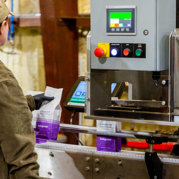 Photo of a Counter Culture Coffee employee sealing a bag of Hologram.