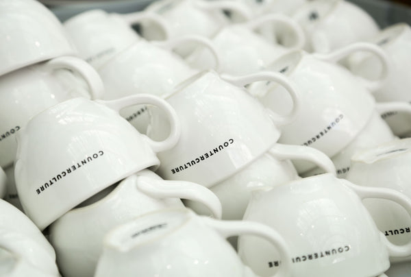 Stack of coffee mugs that all say "Counter Culture Coffee"