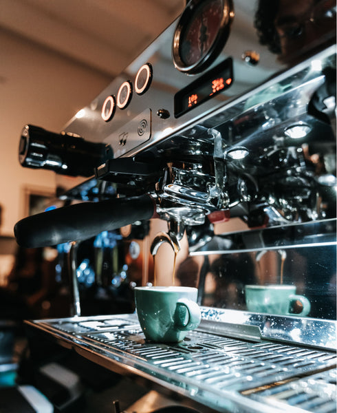 Photo of an espresso machine making espresso into a demitasse cup.