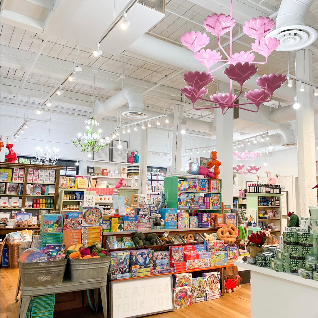 Interior of Parker and Otis. There is a floral chandelier and shelves with merchandise.