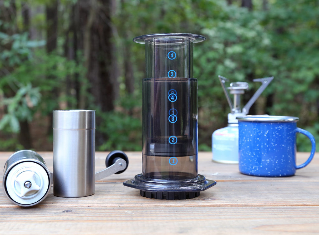 Photo of an AeroPress on a table outside with other coffee supplies.