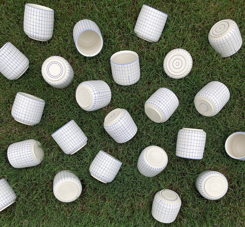 Top down photo of many minimal mugs laying in the grass.