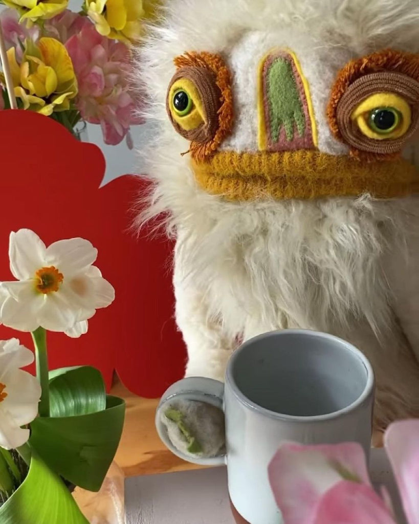 Photo of Wilkins the puppet holding a mug of coffee.