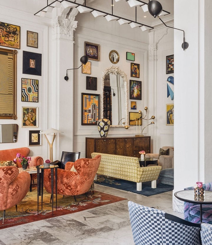Photo of the lobby at the San Francisco Proper Hotel. There are various seating areas and eclectic furnishings. The walls are covered in framed mirrors and art.