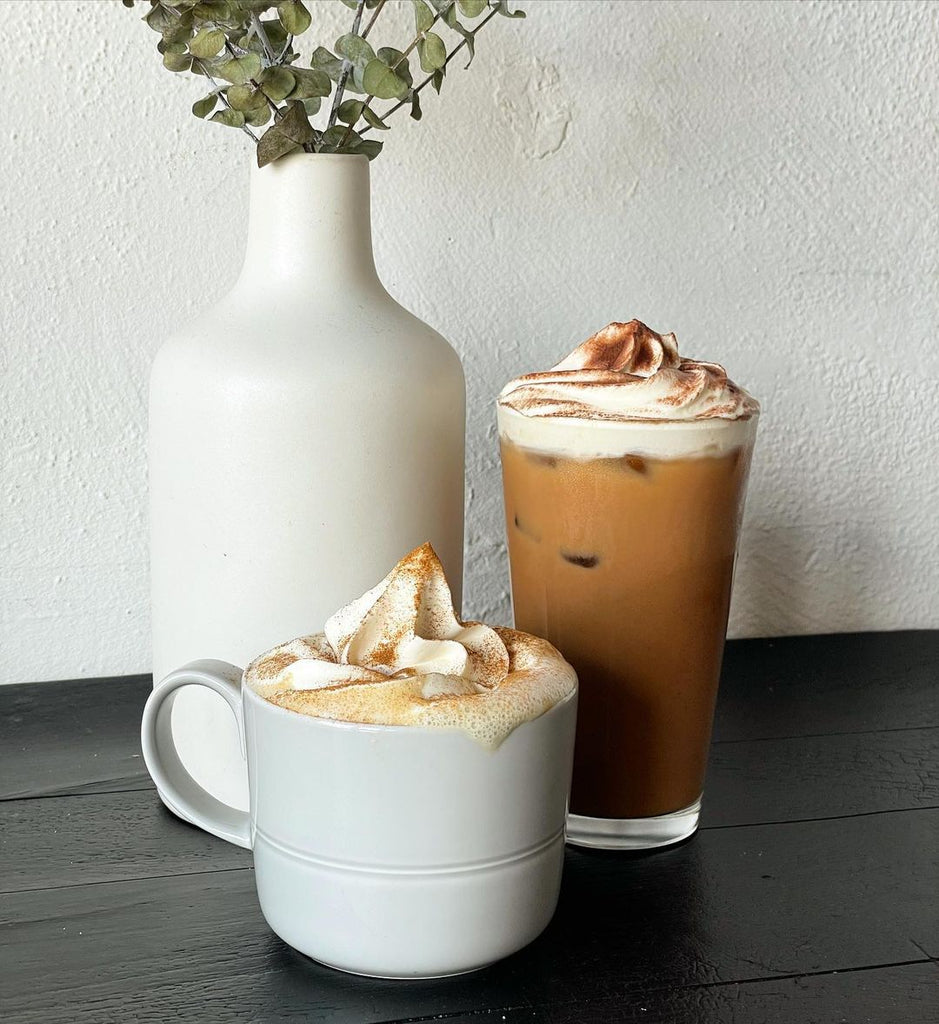 Photo of two coffee based drinks with whipped cream. One is in a mug and one is in a glass.