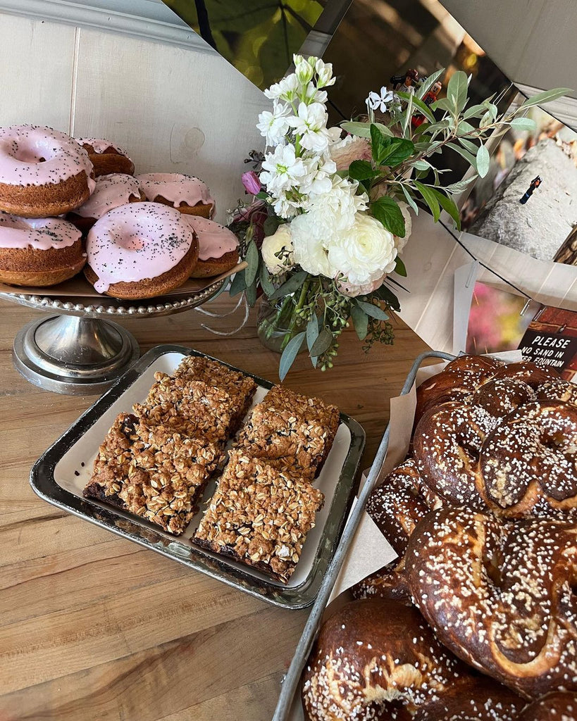 Photo of three different baked goods on trays with a vase of flowers.