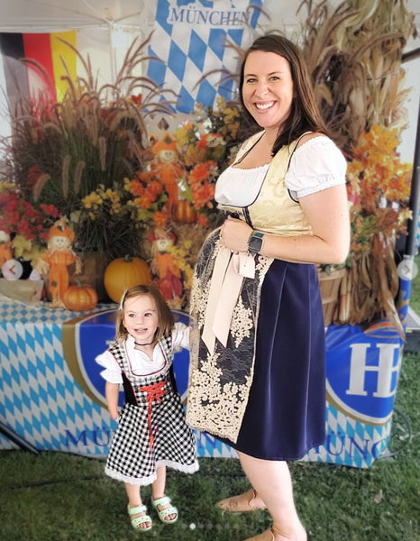 Pregnant woman wearing a dirndl at a local oktoberfest with her daughter