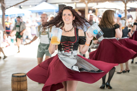 woman dancing in a dirndl dress holding a german beer while spinning