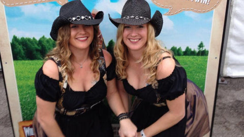 two sisters wearing dirndls and cowboy hats at wurstfest in texas