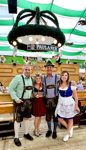 group of people with oktoberfest tickets wearing dirndls and lederhosen on the oktoberfest grounds