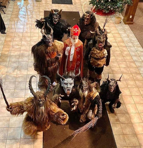 Group of people in demonic masks spiraling horns standing around the kind benevolent saint nicholas