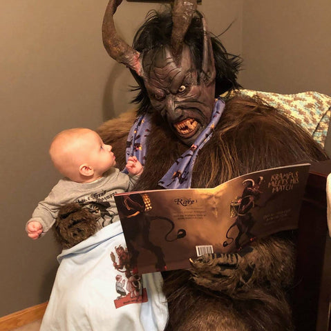 krampus reading the krampus book to a little bald baby