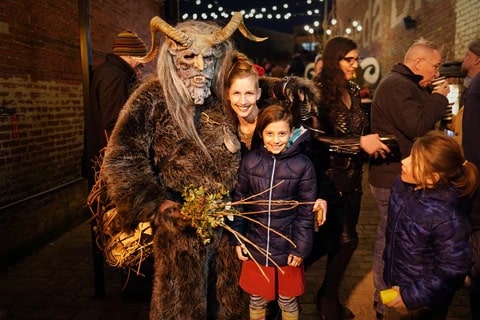 family posting with person in a krampus costume during krampus parade