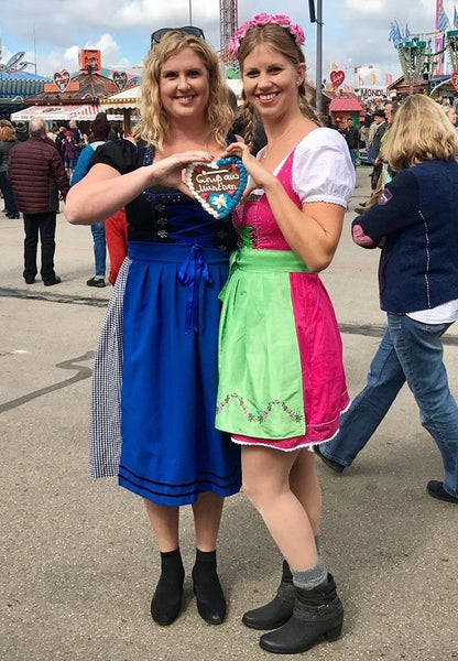 two ladies at oktobefest in dirndls holding a Lebkuchen Herz'l 