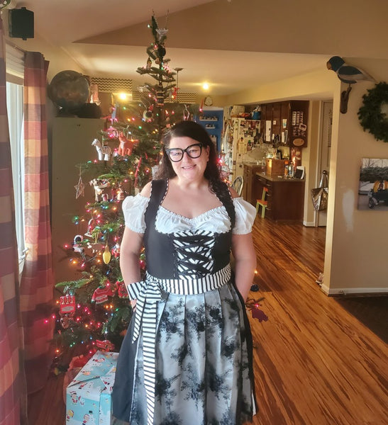woman wearing a plus size black and white dirndl in front of a christmas tree