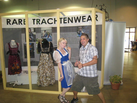 Couple standing in front of brick and mortor Rare Dirndl shop with contemporary style dirndl dresses in the display