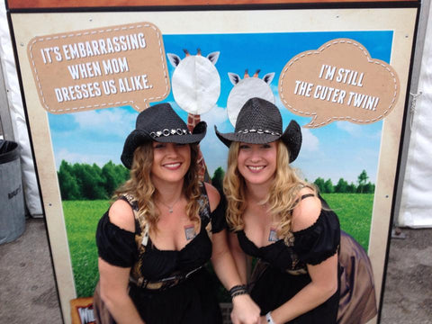 2 girls wearing dirndl dresses and cowboy hats at wurstfest in new braunfels tx near beautiful comal river