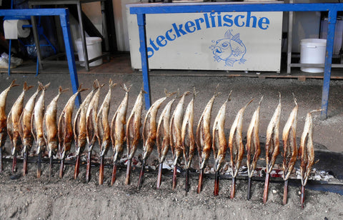 row of steckerlfisched being smoked at oktoberfest in munich. this is a popular and unique oktoberfest food