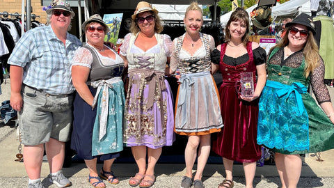 group of women in dirndl and lederhosen smiling and stading together ar German Fest in Milwaukee