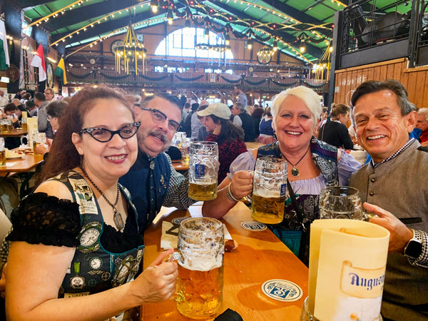 group of people wearing german clothes sitting at a bench in a beer tent