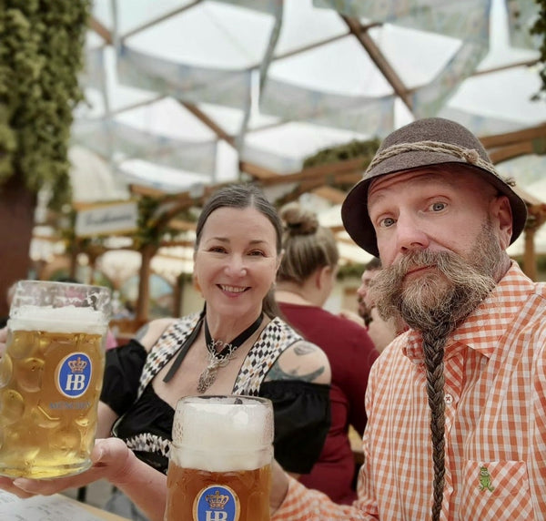 couple holding liters of beer at the spring festival in munich wearing german traditional dress