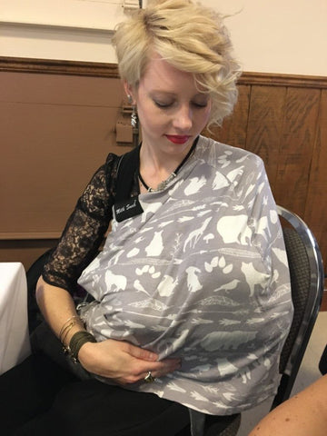 woman wearing a black dirndl and dirndl blouse breastfeeding a baby under a nursing cover