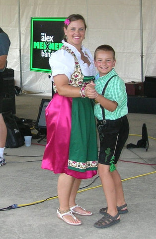woman wearing a bright custom made dirndl dancing with her son dressed in lederhosen