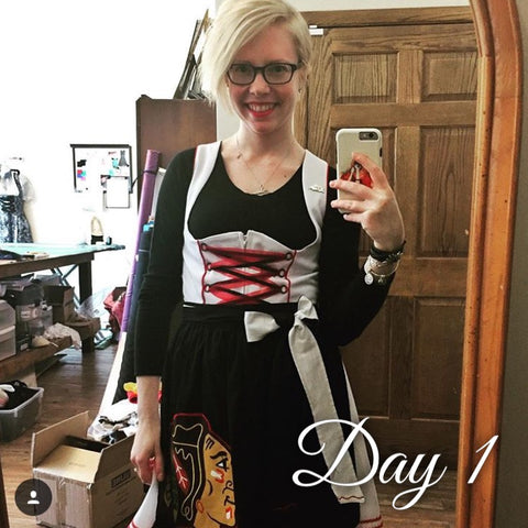 girl taking a selfie wearing a black long sleeve shirt as a dirndl blouse and a white chicago blackhawks themed hockey dirndl